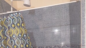 A shower area with a patterned shower curtain, tiled walls, and a handheld showerhead. - Salz Cozy Inn. Comfort at it's best. Peace is guaranteed! (Roseau Valley)