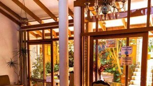 A dining area with a wooden table, chairs, and a chandelier. - Gaudys Hotel (San José)