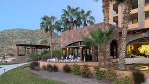 An outdoor dining area with tables and chairs, surrounded by palm trees and a stone building. - Luxury Suite, The Islands of Loreto - stunning natural beauty in Mexico (Loreto)