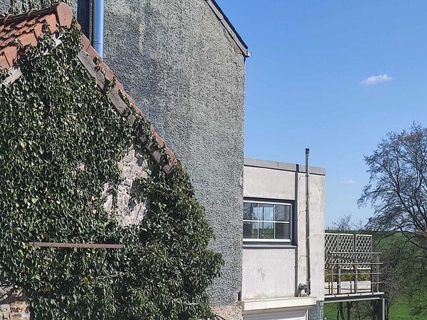 En moderne bygning med en struktureret facade, et vindue og et metalhegn.