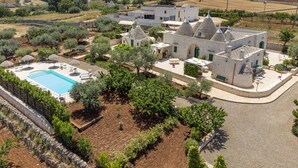 A villa with a swimming pool, outdoor seating, and a garden. - COMPLEX OF TRULLI WITH POOL IN THE COUNTRYSIDE. GREAT POSITION: TRULLETTO  (MARTINA FRANCA)