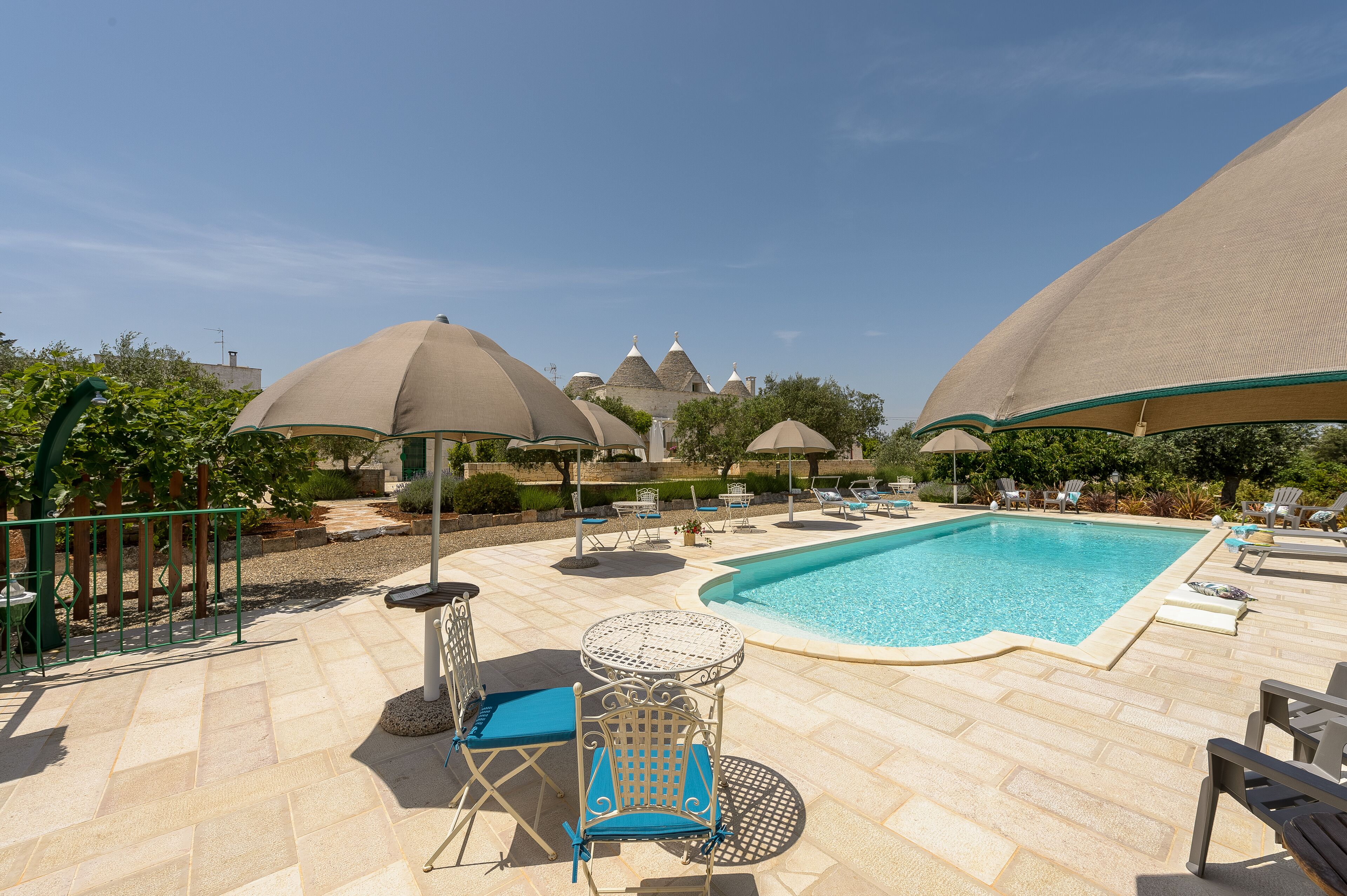 A poolside area with lounge chairs, umbrellas, and a clear view of a building with conical roofs in the background.