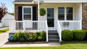 A two-story house with a front porch, a brick section, and a white siding section.