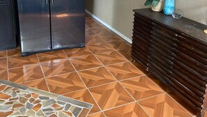 Une cuisine équipée d’un réfrigérateur en acier inoxydable, d’un sol carrelé et d’une armoire en bois.