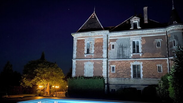 Un grand bâtiment historique doté d’une piscine et d’un espace extérieur aménagé pour s’asseoir.