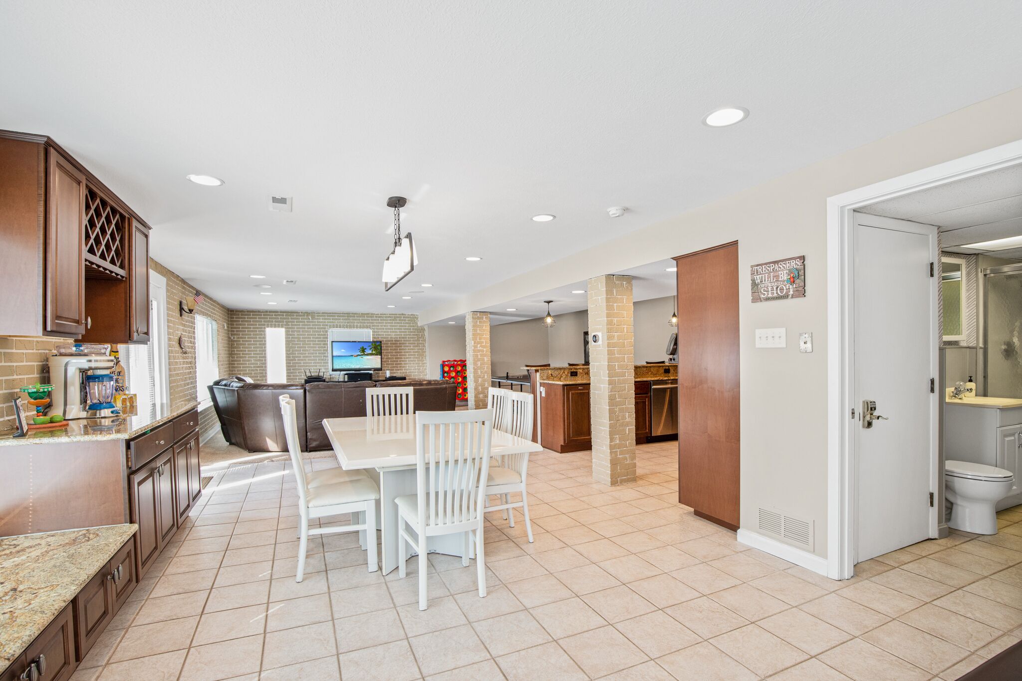 A spacious kitchen with a dining area, a brick accent wall, and a modern ceiling light fixture.