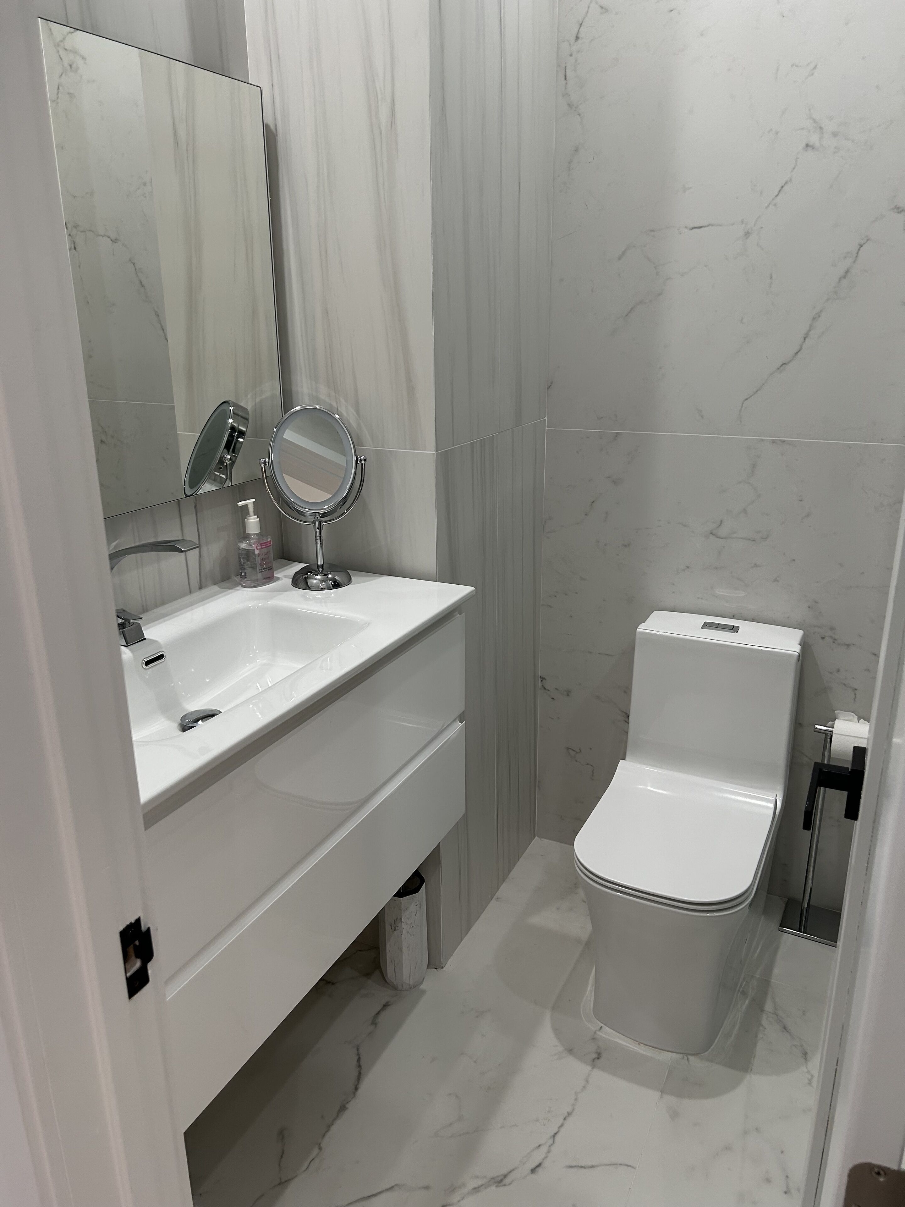 Une salle de bain moderne avec un lavabo blanc, un miroir et des toilettes.