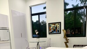 Un dormitorio moderno con una cama, una mesita pequeña y sillas. Hay un armario y una ventana con vistas a árboles.