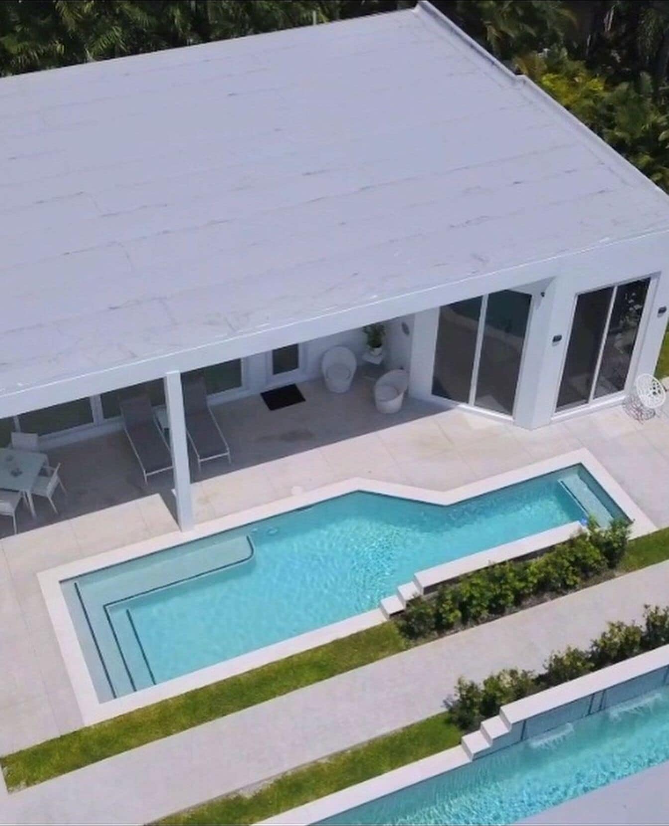 Ett modernt hus med en stor swimmingpool och en täckt uteplats.