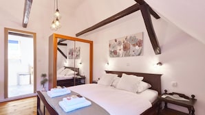 Une chambre avec un grand lit, des poutres en bois, un miroir et un tableau au mur.