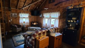 Interior acogedor de una cabaña con chimenea, muebles de cuadros y una barra de café.