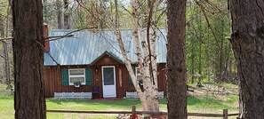 A wooden cabin with a metal roof, a welcome sign, and a white picket fence. - Wood Haven Lodge. Secluded, cozy log cabin in Northern Michigan. (South Boardman)