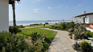 Um caminho que leva a uma praia, com vista para o oceano e um píer ao longe.