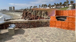 Uma área costeira com falésias rochosas, praia e um banco de pedra.