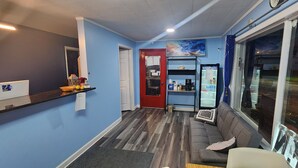 Un interior moderno con mostrador de recepción, un sofá, un refrigerador y una puerta que da a otra habitación.