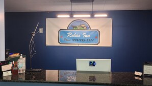 Una mesa de recepción con un cartel que dice "Relax Inn" y un número de teléfono.