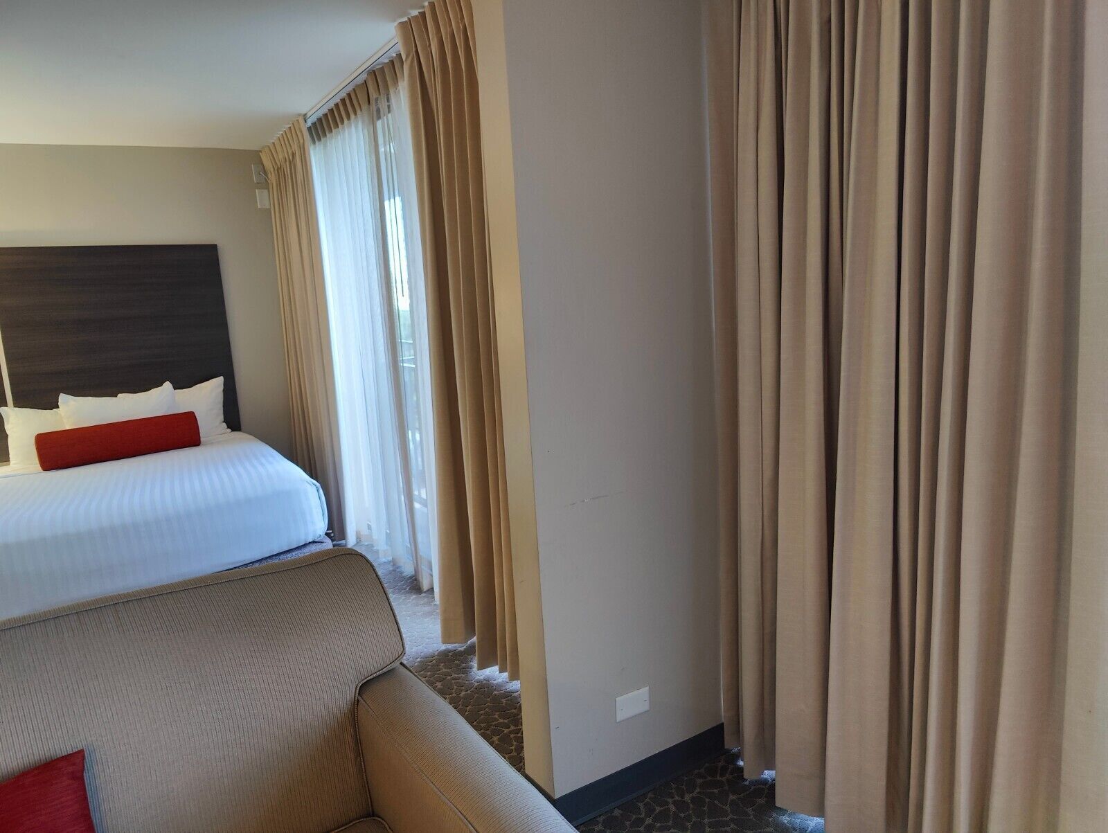 A hotel room with a bed, a sofa, and curtains.