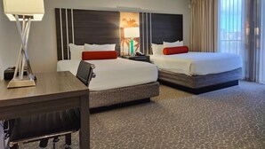 A hotel room with two beds, a desk, a lamp, and a view of the city. - Large Studio w/ Pool sleeps six in comfort PLUS FREE PARKING INCLUDED! (Honolulu)