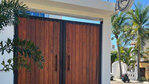 Un edificio moderno con un'ampia porta di legno, un cartello con un logo e una palma sullo sfondo.
