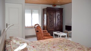 A bedroom with a bed, a wooden wardrobe, a chair, a small table, and a television. - Amazing home in Quemperven with WiFi (Quemperven)