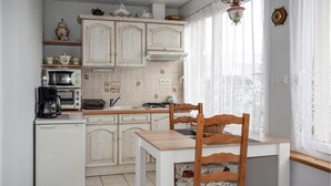 A kitchen with white cabinets, a coffee maker, a toaster, and a dining table with chairs. - Amazing home in Quemperven with WiFi (Quemperven)