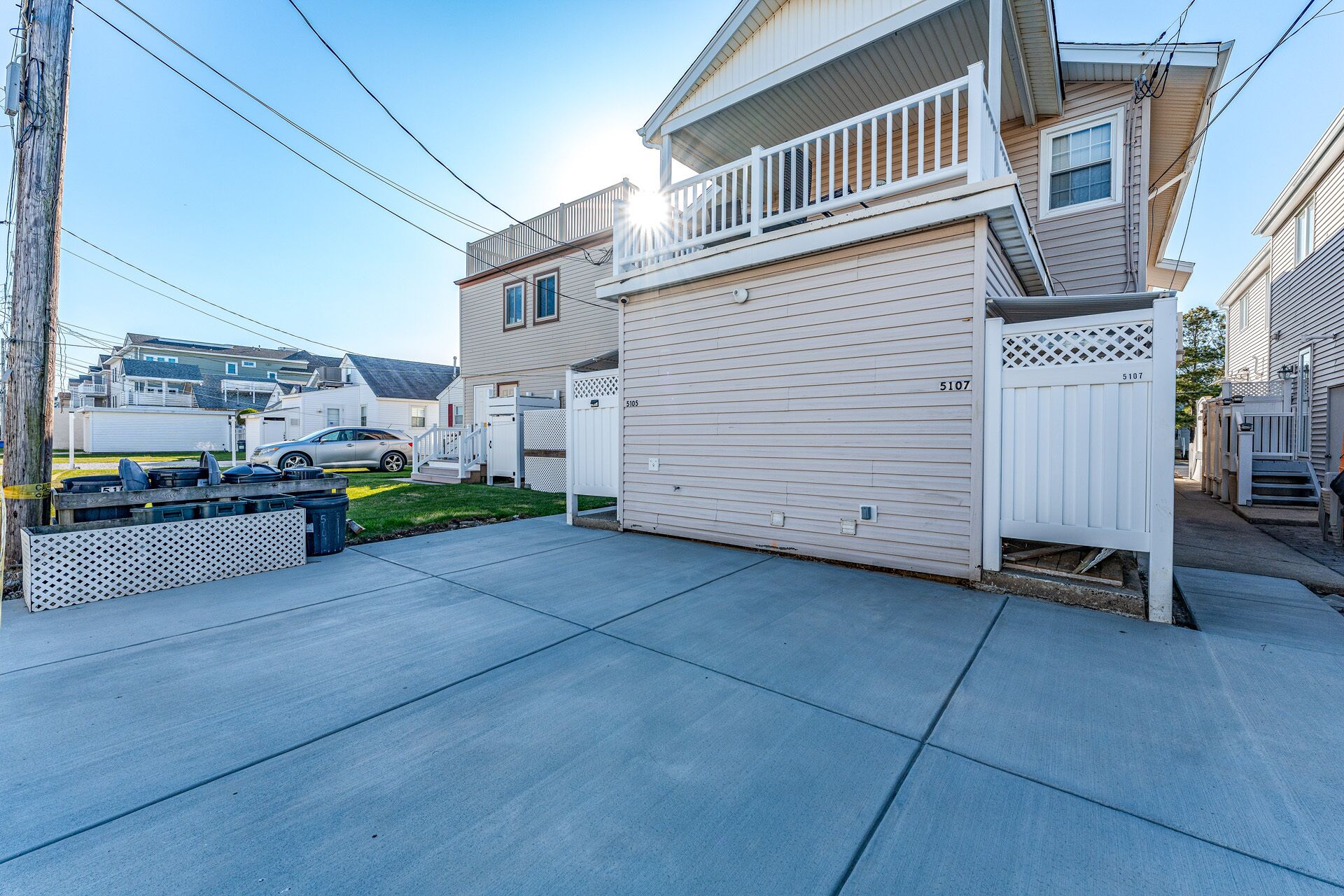 A residential area with a garage door, a white fence, and a parked car.