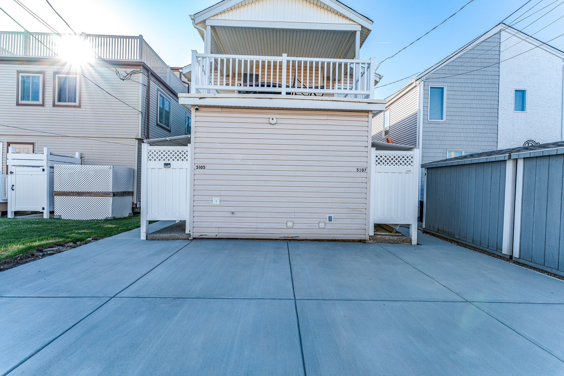 A residential garage with a covered upper level, a fenced yard, and a clear sky.