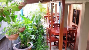 Un petit coin repas avec une table et des chaises en bois, entouré de plantes en pot.