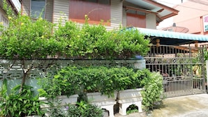 Une maison avec un balcon, un portail en métal et une variété de plantes.