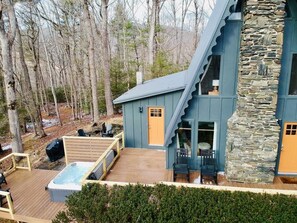 Ein modernes Haus mit Natursteinfassade, einer Holzterrasse und einem Whirlpool.