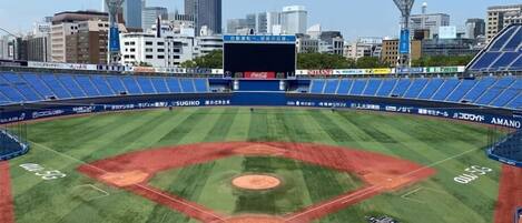 A baseball stadium with a clear view of the field, advertisements, and city skyline in the background.