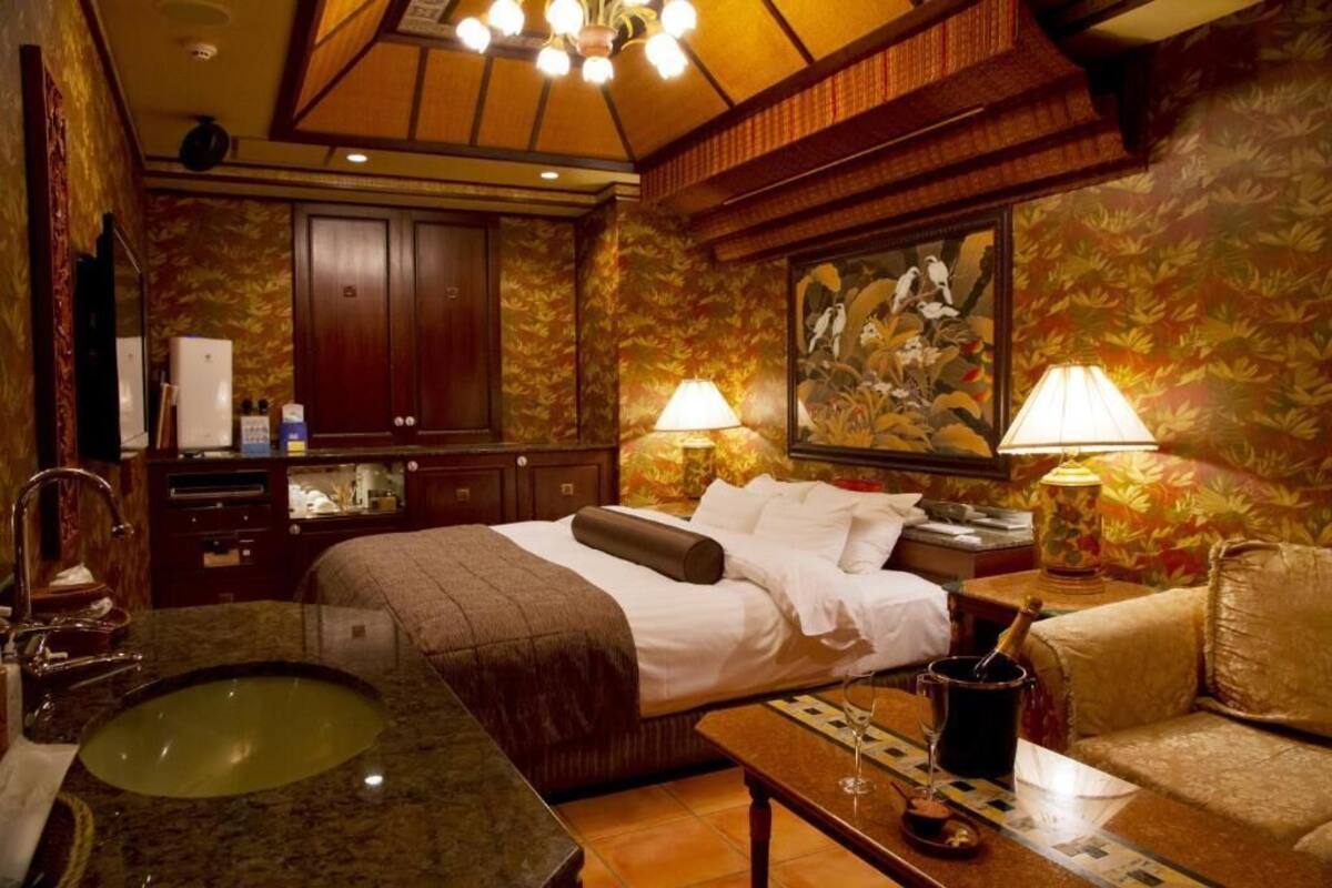 A hotel room with a bed, a large sink, a wooden cabinet, a painting on the wall, and two lamps.