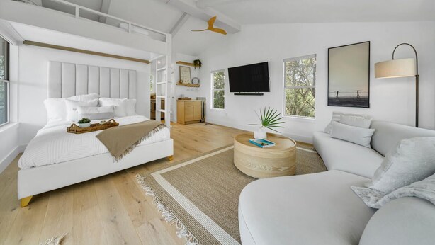 A modern bedroom with a bunk bed, a flat-screen TV, a large window with a view, and a ceiling fan.