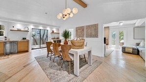 A modern kitchen with a built-in dishwasher, wooden cabinets, and a dining area with a white table and chairs.