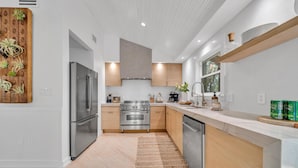 A modern kitchen with stainless steel appliances, wooden cabinets, and a large island.