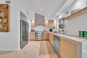 A modern kitchen with stainless steel appliances, wooden cabinets, and a large island.