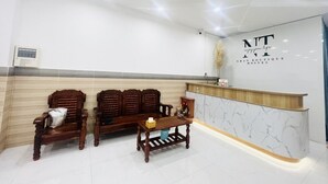 A reception area with a marble counter, wooden chairs, and a small table. - Nhan Tay Hostel (Can Tho)
