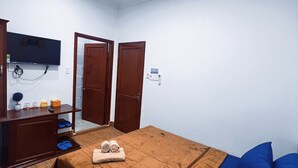 A bedroom with a bed, a TV mounted on the wall, a wooden dresser, and a door. - Nhan Tay Hostel (Can Tho)