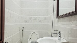 A bathroom with a toilet, sink, shower, and a mirror. - Nhan Tay Hostel (Can Tho)