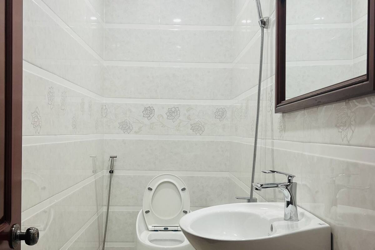 Une salle de bain équipée de toilettes, d’un lavabo, d’une douche et d’un miroir.