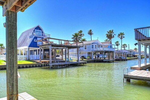 A waterfront property with multiple docked boats, a large blue building, and a wooden deck.