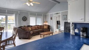 A spacious living area with a large brown sectional sofa, a coffee table, and a ceiling fan. - Bahama Waves (Jamaica Beach)