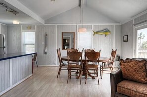 Un espace repas avec une table et des chaises en bois, un comptoir de cuisine et une vue sur l’extérieur.