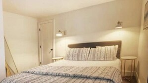 A bedroom with a bed, two bedside tables, and a door. - Walk to downtown and only a block from the river! (Bend)