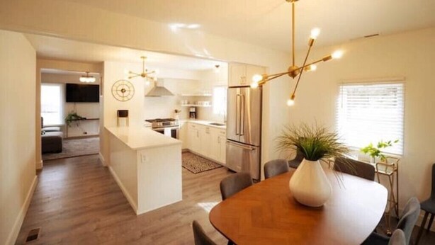 A modern kitchen with a central island, stainless steel appliances, and a dining area with a wooden table and chairs. - Walk to downtown and only a block from the river! (Bend)