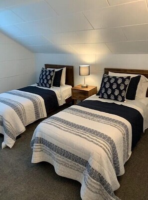 A hotel room with two beds, each with a patterned pillow and a bedside lamp. - Walk to downtown and only a block from the river! (Bend)
