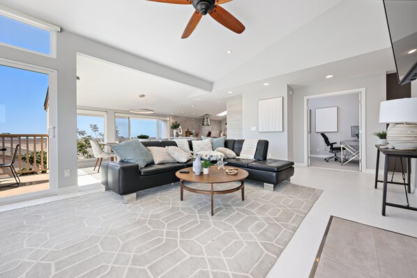 A spacious living room with a sectional sofa, a round coffee table, and a ceiling fan.