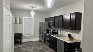 A modern kitchen with dark cabinets, stainless steel appliances, and a granite countertop. - Hickory Landing (Nashville)