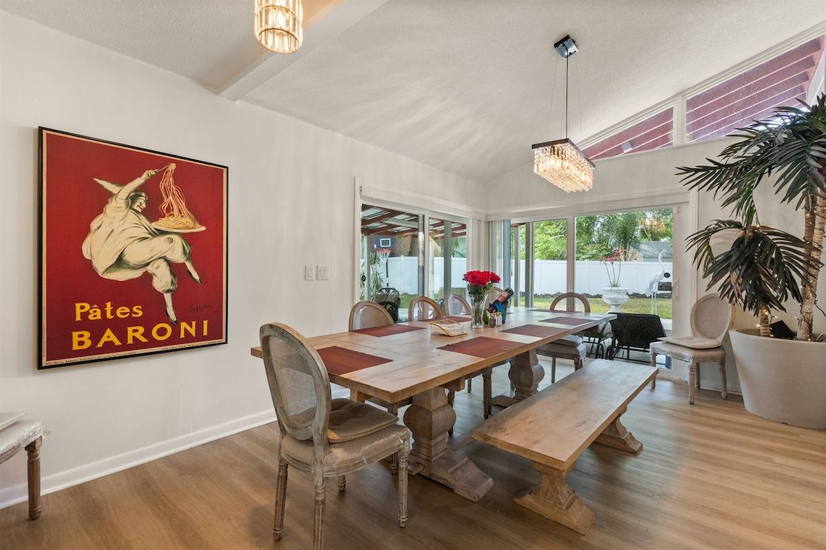 A dining area with a large wooden table, chairs, and a large framed artwork on the wall.