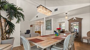 A dining area with a large wooden table, vintage chairs, and a chandelier.